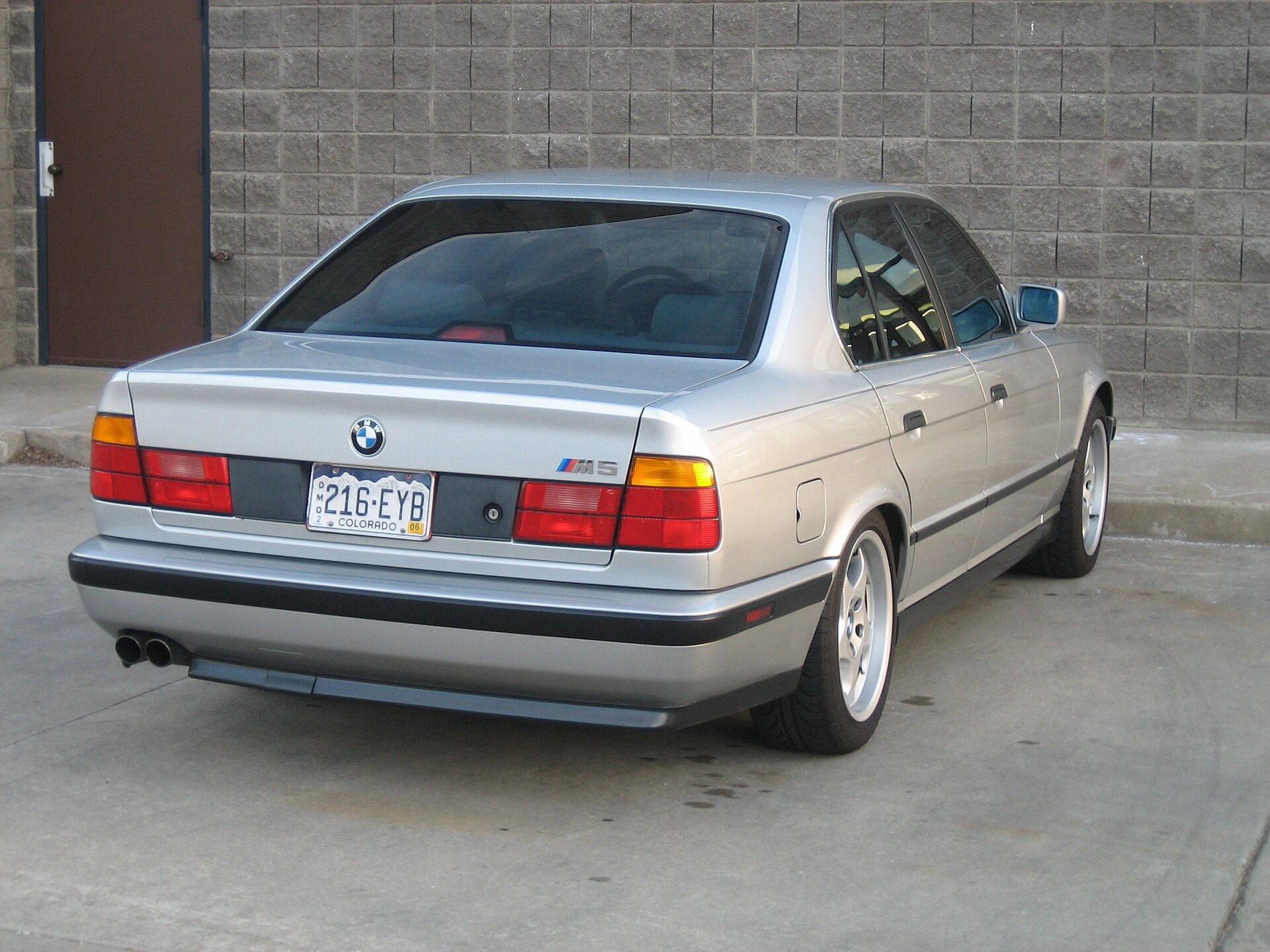 BMW E34 M5 Limousine in Silber mit M-System-Felgen, Heckansicht schraeg